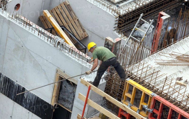 A construction worker juggles with an iron bar in his hand on a building site at lofty heights, Berlin, 18/08/2016
