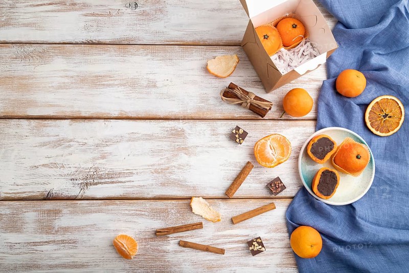 Truffle chocolate tangerine candies on a white wooden background and blue linen textile. top view, flat lay, copy space