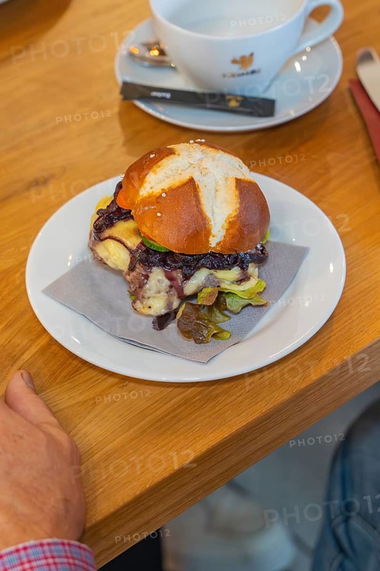 A burger on a pretzel bun with a napkin on a plate, autumn creations, Cafe Kuh, Deckenpfronn, Black Forest, Germany, Europe