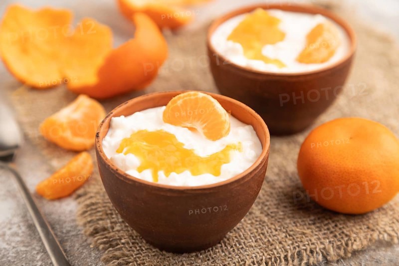 Grained cottage cheese with tangerine jam on brown concrete background and linen textile. side view, close up, selective focus