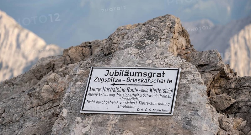 Signpost for difficult mountain tour, signpost Jubiläumsgrat in the evening light, steep rocky mountain landscape, Wetterstein range, Bavaria, Germany, Europe