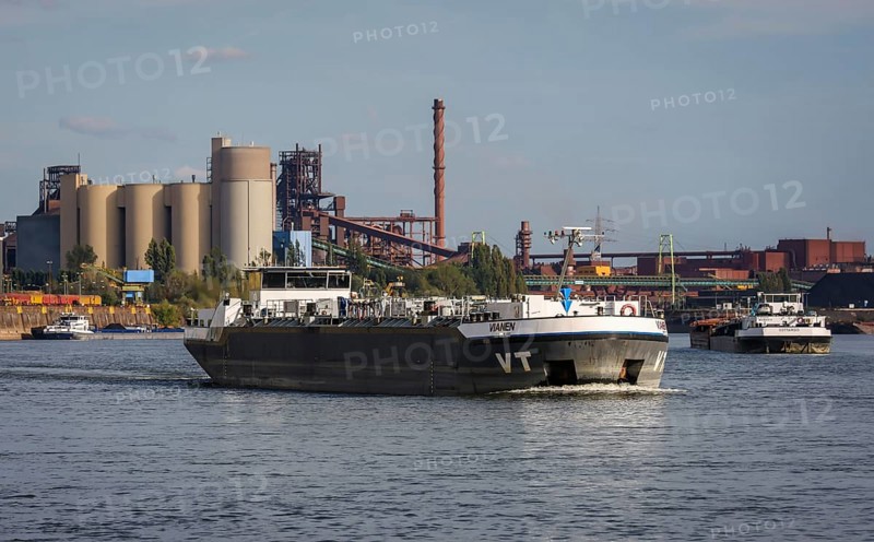 Duisburg, North Rhine-Westphalia, Germany, freighter at the southern harbour, Holcim cement works at the rear left, ThysseKrupp Steel blast furnace Schwelgern in Duisburg Marxloh at the rear right. Due to the draught, freighters can only navigate the Rhine with a small load and sometimes park in front of the entrance to Duisburg harbour due to the low water level, Europe