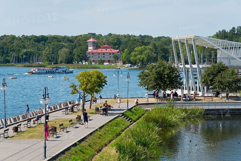 A lively lakeside promenade with a view of the lake, boats and an architectural bridge in the background, Gizycko, Warminsko-Mazurskie, Warminsko-Mazurskie, Poland, Europe