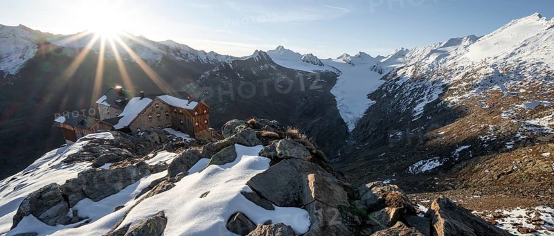 Mountain panorama and glacier, mountain hut Ramolhaus in autumn with snow, view of Gurgler Ferner with summit Hochwilde and Falschungsspitze, at sunrise with sun star, Ötztal Alps, Tyrol, Austria, Europe