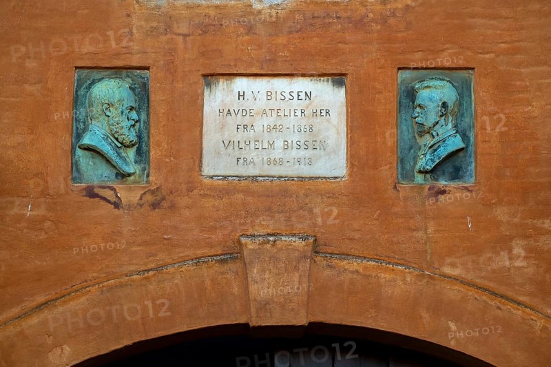 Commemorative plaque with portraits of H. V. Bissen and Vilhelm Bissen above entrance gate, studio, rust-red house, Frederiksholms Canal, Copenhagen, Denmark, Europe