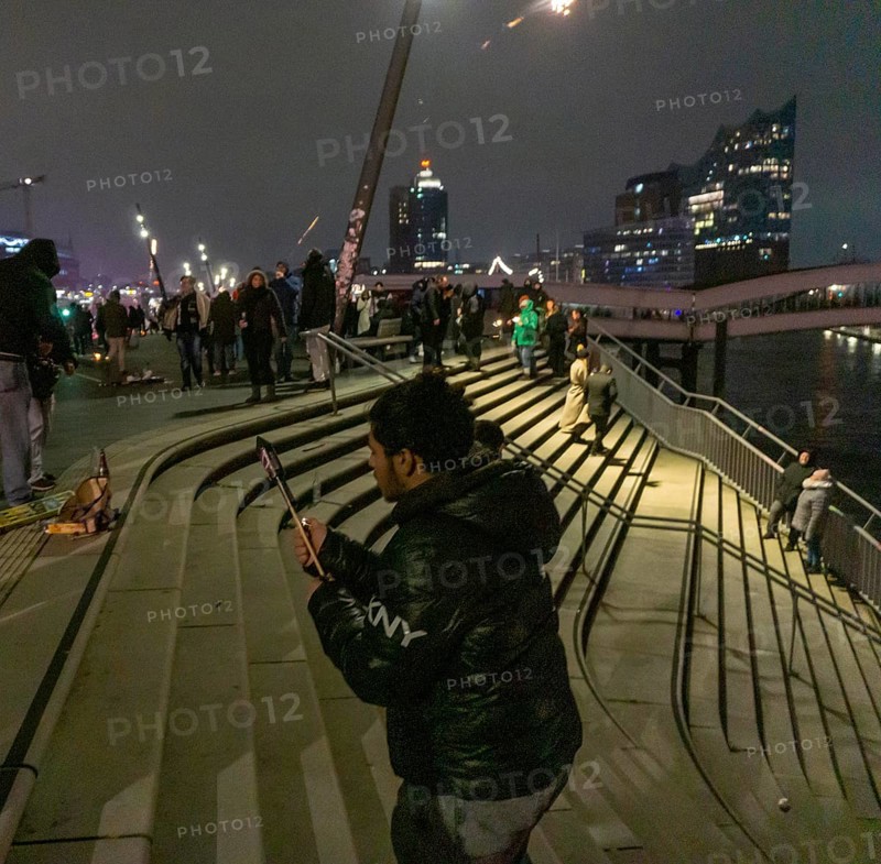Person launches firework rocket from his hand, New Year's Eve 2025 on the Elbe promenade in Hamburg, at the harbour, on the Elbe, fire brigade of many thousands of people, Jan Fedder promenade