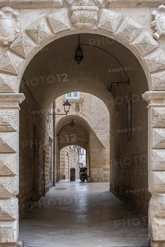 Narrow corridor with arches and stone walls, illuminated by ancient lanterns in a historic neighbourhood, Altamura, Apulia, Italy, Europe