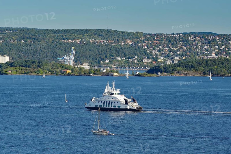 A ferryboat in the calm sea, with an urban landscape and green hills in the background, electric ferry, Oslofjord, capital city, Oslo, Norway, Europe