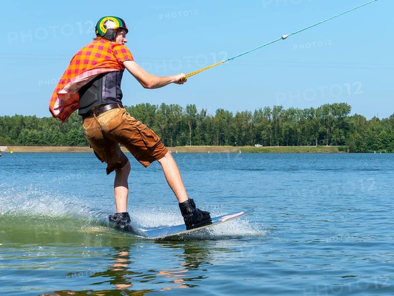 Young casual man with flapping shirt on wakeboard in lake, water ski and wakepark, Stráž pod Ralskem, Czech Republic, Europe