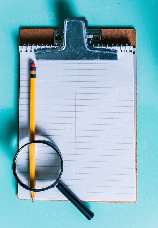 Notepad with pencil and magnifying glass on isolated background. Note book with magnifying glass and pencil on clipboard