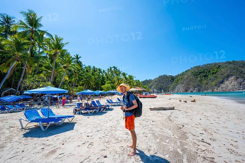 Tourist on a sandy beach with deckchairs, tropical island with palm trees and turquoise blue sea, Isla Tortuga, Puntarenas province, Costa Rica, Central America
