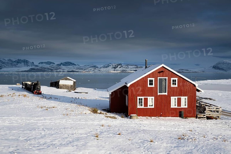 Historic mine railway and red house in front of the wintry, snow-covered Kongsfjorden, Ny-Ålesund, Spitsbergen Island, Svalbard and Jan Mayen archipelago, Norway, Europe