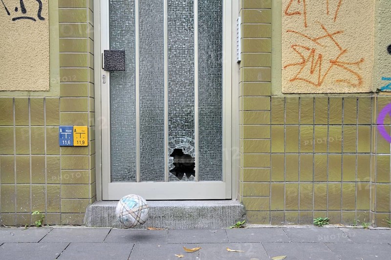Shattered glass pane on a front door and football, Germany, Europe
