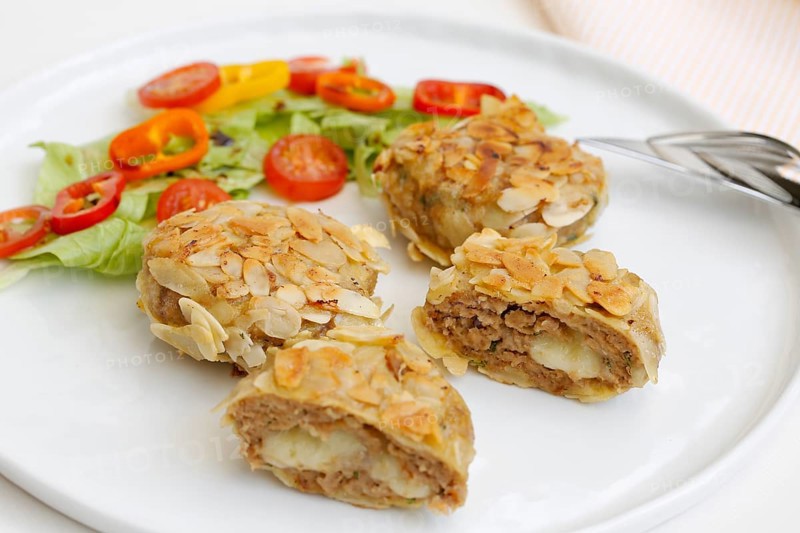 Swabian cuisine, meatballs wrapped in almonds, mixed minced meat, meatballs filled with cheese, fried, meatballs, grandmother's cooking, regional, home cooking, typical Swabian, traditional cuisine reinterpreted, served on a plate with salad, lettuce, cherry tomatoes, cocktail tomatoes, peppers, food photography, studio, Germany, Europe