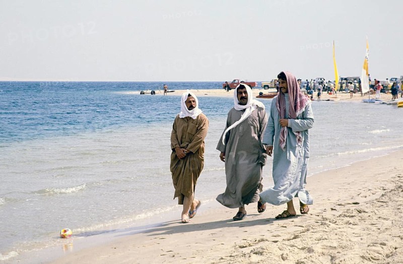 Leisure time, sailing club for foreign workers, Half Moon Bay, Saudi Arabia 1979 three local Saudi men walking on the beach