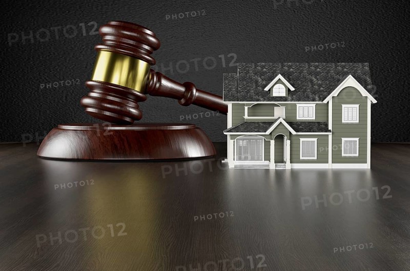 Wooden gavel and miniature house on a wood surface