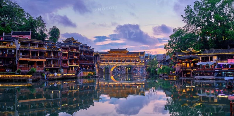 Chinese tourist attraction destination, panorama of Feng Huang Ancient Town (Phoenix Ancient Town) on Tuo Jiang River illuminated at night. Hunan Province, China, Asia
