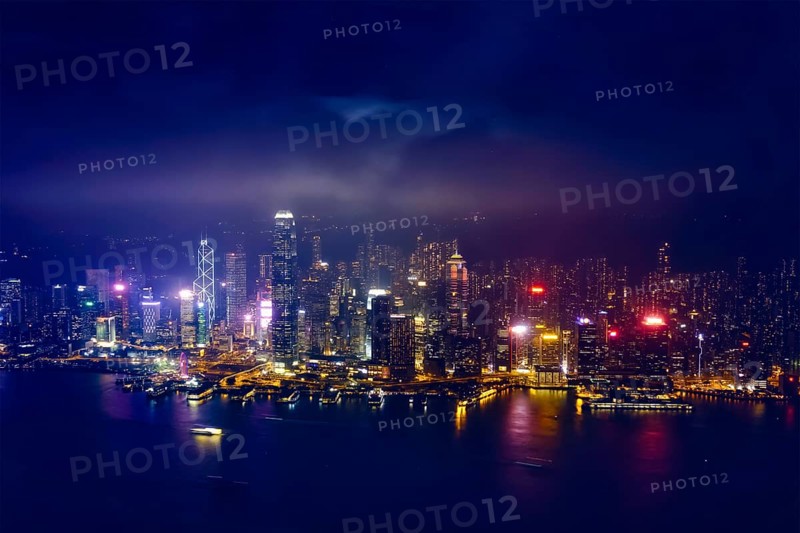Aerial view of illuminated Hong Kong skyline cityscape downtown skyscrapers over Victoria Harbour in the evening. Hong Kong, China, Asia