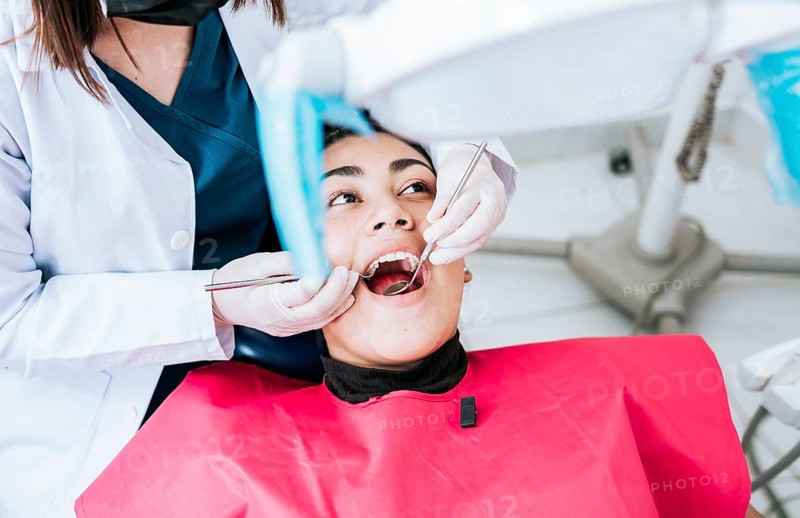 Top view of dentist doing cleaning to female patient lying down. Dentist doctor examining mouth to patient lying on chair, Female dentist examining mouth to patient lying down