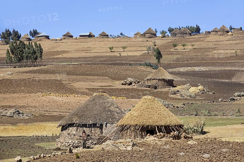 Farmer in front of traditional round stone huts with thatched roofs in the Ethiopian highlands, Lasta Amhara Region, Ethiopia, Africa