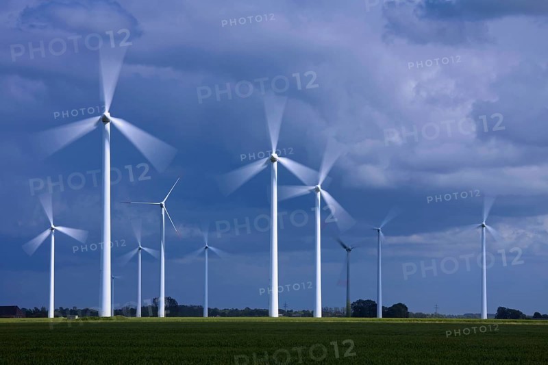 Spinning blades of wind turbines at the wind farm against stormy skies