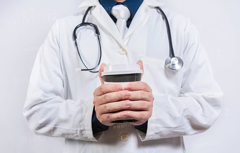 Hands of doctor holding takeaway coffee on isolated background. Doctor hands holding paper coffee