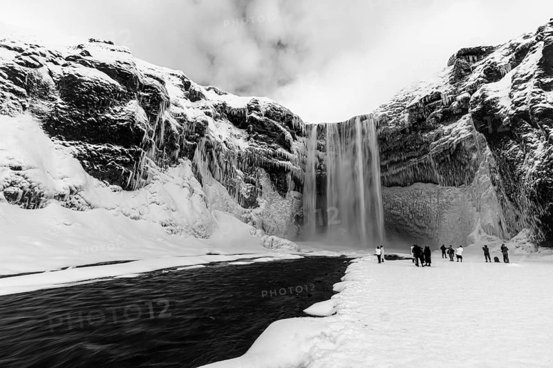 Skogafoss waterfall with icy and snowy rock face, black and white photo, Sudurland, Iceland, Europe