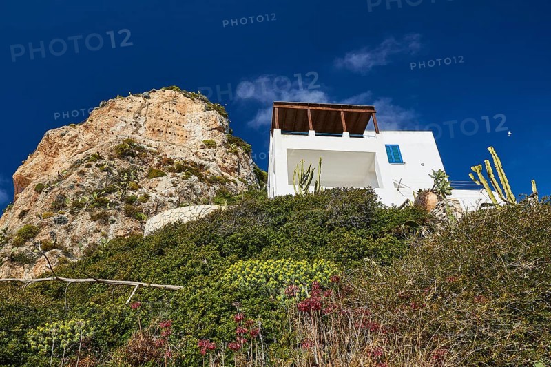 Green slope, rocky outcrop, white house, Levanzo village, Levanzo, Egadi Islands, Sicily, Italy, Europe