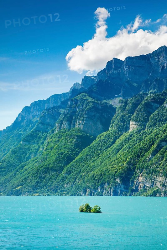 Sunny view over Lake Walen with the small chive island in the turquoise water and mountain range Schären and Leistchamm in the background, Canton St. Gallen, Switzerland, Europe