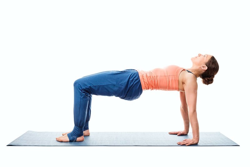 Woman doing Ashtanga Vinyasa Yoga asana Purvottanasana, upward-facing plank pose posture easy variation isolated on white background