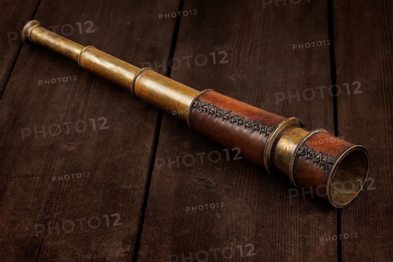Vintage retro spyglass on wooden background