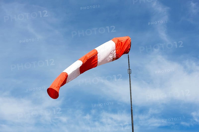 White-red windsock against blue sky, cloudy, wind vane, Germany, Europe