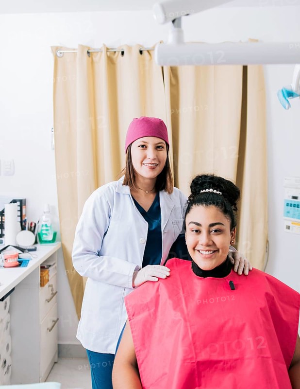 Portrait of dentist with patient smiling at camera in office, Female dentist with satisfied patient smiling at camera, Female dentist with patient smiling friendly