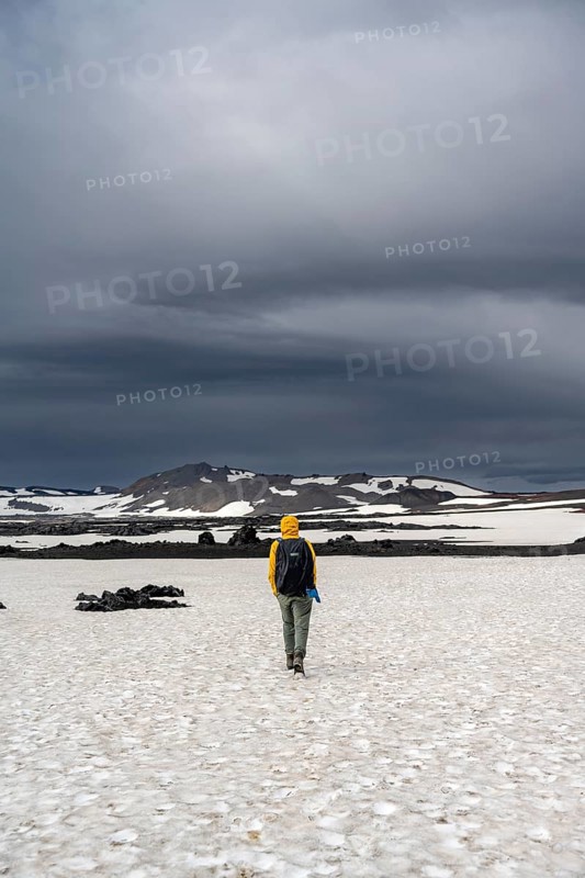 Hikers in snow-covered volcanic landscape with volcanic sand and petrified lava, crater of Askja volcano, Icelandic highlands, Iceland, Europe