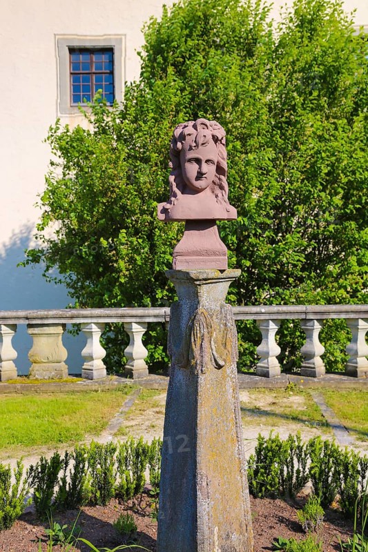 Stone figure, bust, statue in the castle park, woman's face, behind moated castle Geislingen, three-winged moated castle complex, former manor house of the Lords of Bubenhofen, since the 18th century baroque three-winged complex of the Schenken von Stauffenberg, architecture, historical building, sandstone balustrade, Geislingen, Zollernalbkreis, Baden-Württemberg, Germany, Europe