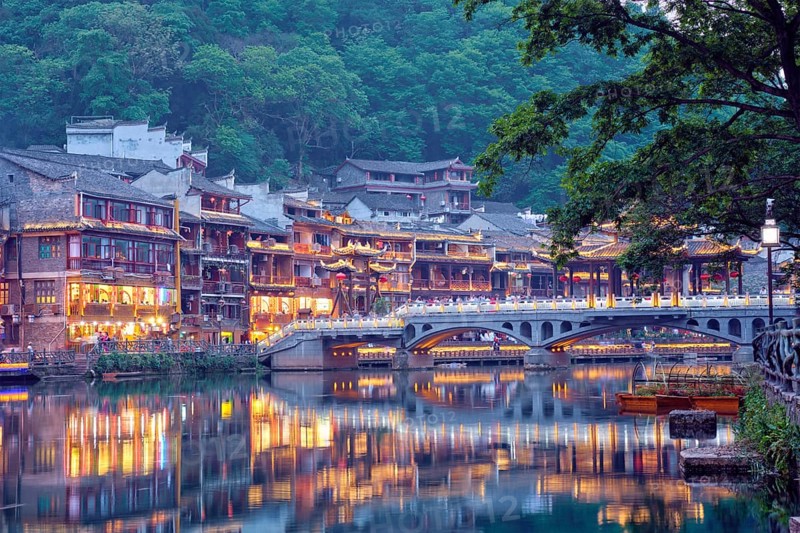 Chinese tourist attraction destination, Feng Huang Ancient Town (Phoenix Ancient Town) on Tuo Jiang River with bridge illuminated at night. Hunan Province, China, Asia
