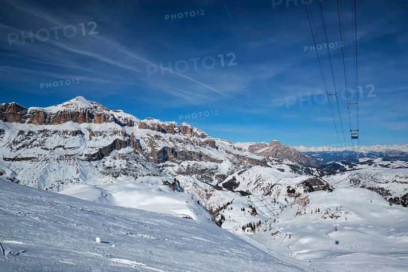 View of a ski resort piste with people skiing in Dolomites in Italy with cable car ski lift. Ski area Arabba. Arabba, Italy, Europe