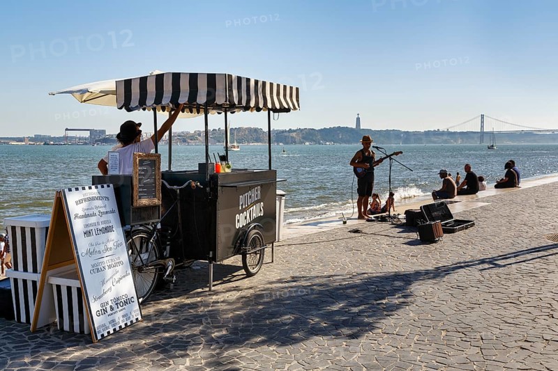 Lively terrace on the banks of the Tagus, drinks kiosk, backlit street musicians, Ribeira das Naus, Lisbon, Portugal, Europe