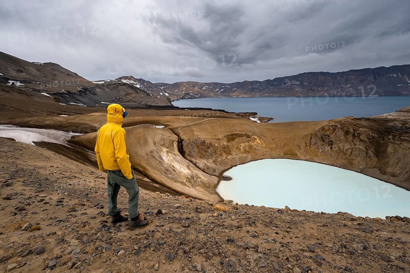 Tourist at the crater rim, crater lake Víti and Öskjuvatn in the crater of Askja volcano, volcanic landscape, mountain massif Dyngjufjöll, Icelandic highlands, Vatnajökull National Park, Iceland, Europe