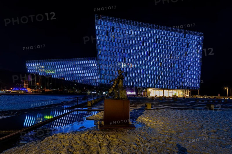 Bronze statue of the man with the cello, behind it the illuminated facade of the concert hall and congress centre Harpa, night shot, Reykjavik, Reykjanes Peninsula, Sudurnes, Iceland, Europe