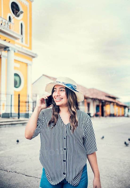 Happy travel woman calling on the phone in a tourist plaza. Beautiful tourist girl talking on cell phone in the square. Granada, Nicaragua, Central America
