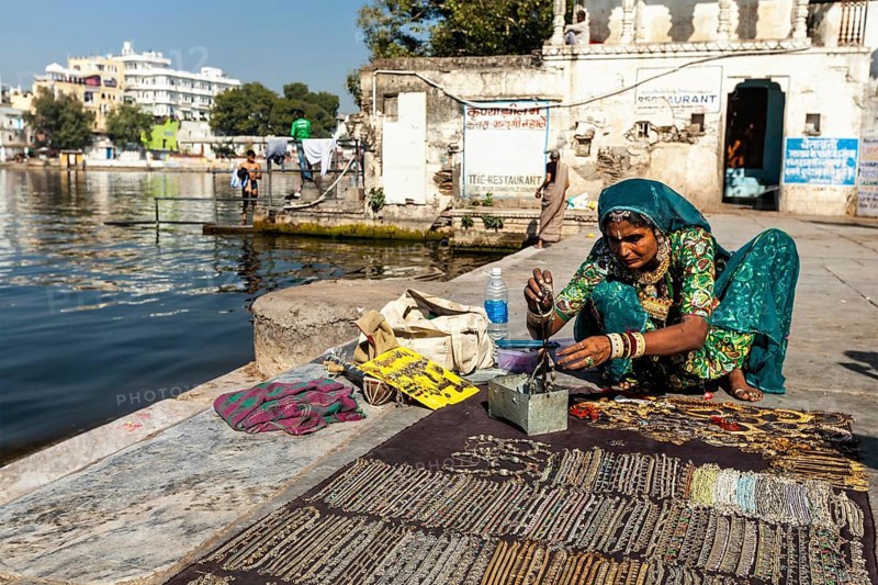 UDAIPUR, INDIA, NOVEMBER 24, 2012: Woman street vendor in traditional clothing selling jewellery on ghat of Lake Pichola. Udaipur, Rajasthan, India, Asia