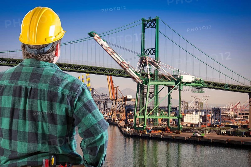 Male worker wearing yellow hard hat overlooking the san pedro ship yard and bridge