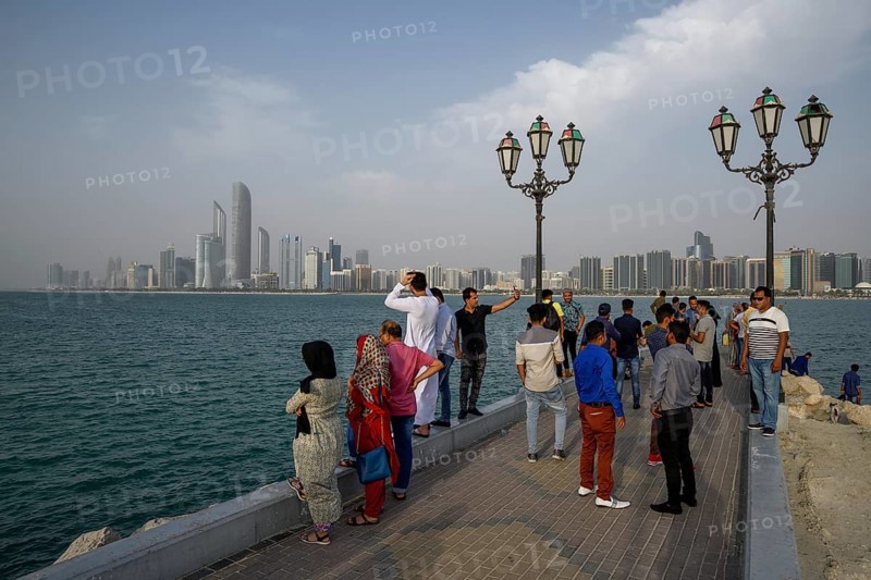 Locals in front of skyline at Wave Breaker Beach vantage point, Abu Dhabi, Abu Dhabi Emirate, United Arab Emirates, Asia