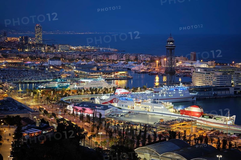 BARCELONA, SPAIN, APRIL 15, 2019: Aerial view of Barcelona city skyline with city traffic and port with yachts and ferry ships illuminated in the night. Barcelona, Spain, Europe