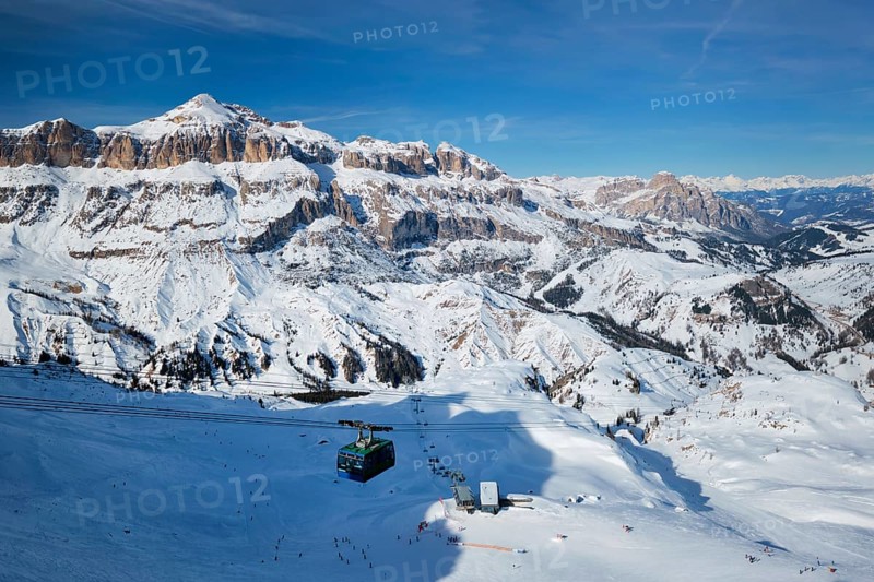 View of a ski resort piste with people skiing in Dolomites in Italy with cable car ski lift. Ski area Arabba. Arabba, Italy, Europe