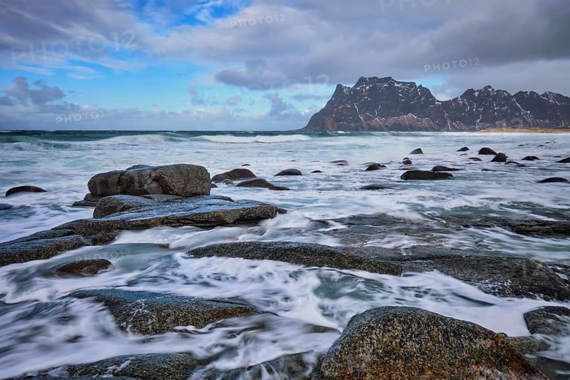 Rocks on beach of fjord of Norwegian sea in winter with snow. Utakliev beach, Lofoten islands, Norway, Europe