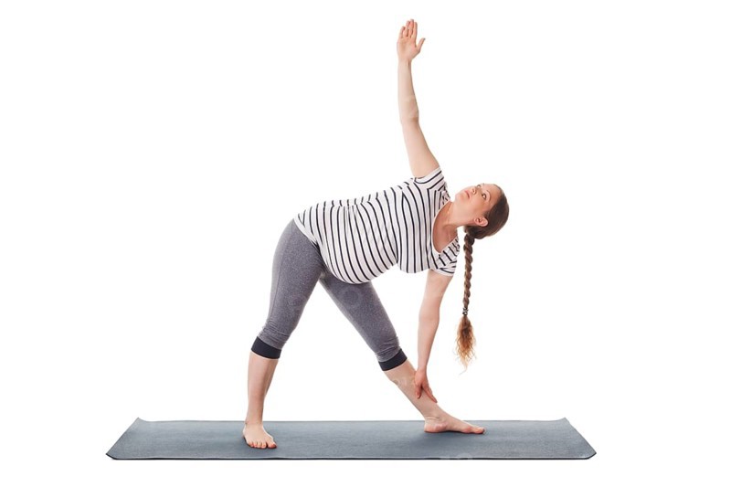 Pregnancy yoga exercise, pregnant woman doing asana Utthita trikonasana, extended triangle pose isolated on white background