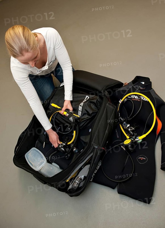 Young woman packing suitcase with diving luggage with maximum dimensions for sports luggage in charter plane for air travel, Germany, Europe