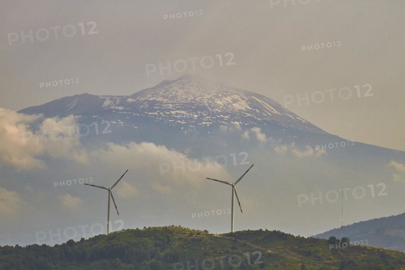 Two wind generators on a green hill, snow-capped Mount Etna in the background, Nebrodi National Park, Sicily, Italy, Europe